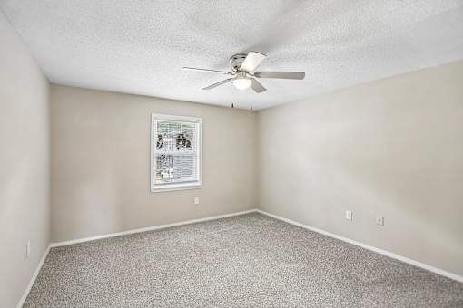A room with a ceiling fan and a window with blinds.