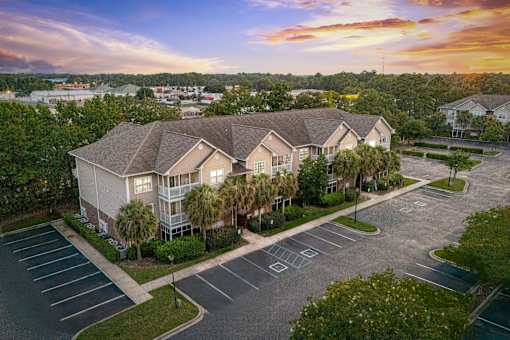 A sunset view of a residential area with apartment buildings and a parking lot.