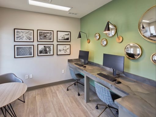 a computer desk with two monitors in a room with pictures on the wall