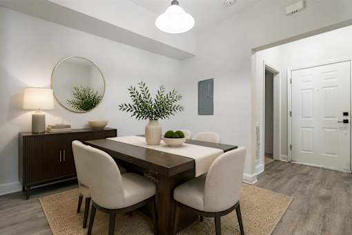 A dining room with a wooden table and white chairs.