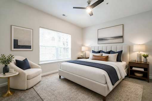 A bedroom with a large bed, a chair, and a ceiling fan.