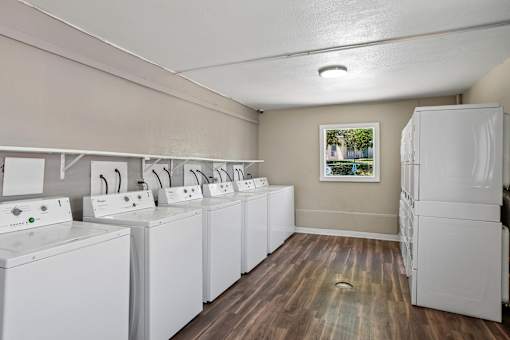 A laundry room with a row of washers and dryers.