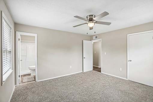 A room with a ceiling fan and carpeted floor.