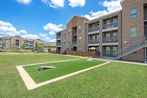 A grassy area in front of apartment buildings with a small toy airplane on the ground.