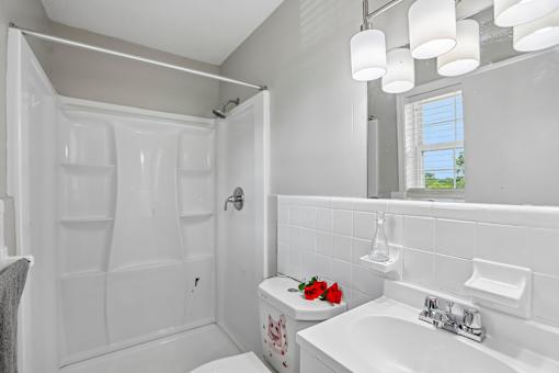 A white bathroom with a toilet, sink, and shower.
