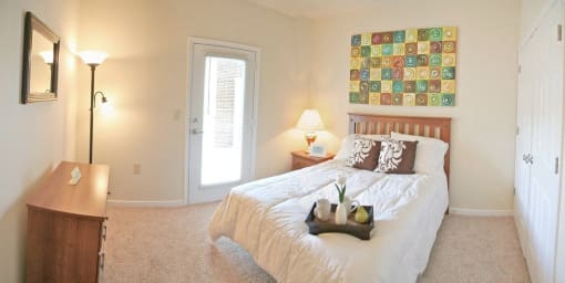a bedroom with a bed and a painting on the wall at Chester Village Green Apartments, Virginia