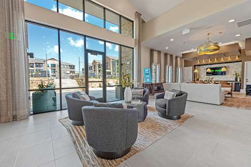 A spacious living room with grey armchairs and a large window overlooking a construction site.
