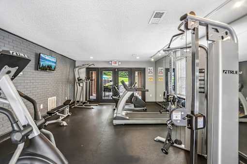 A gym with a variety of equipment including treadmills, weights, and exercise machines.