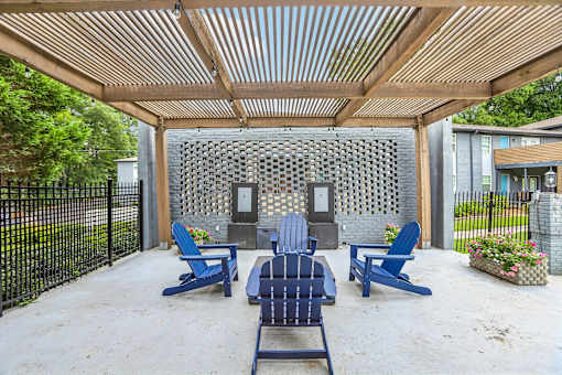 A patio with blue chairs and a wooden pergola.