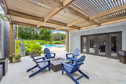 A patio with blue chairs and a wooden roof.