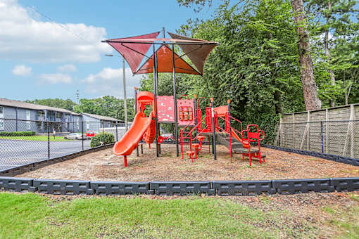 A playground with a red slide and a red canopy.
