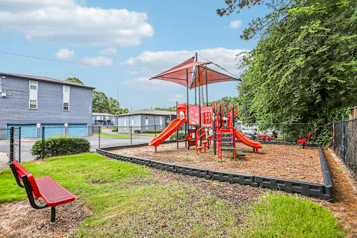 A playground with a red slide and a red bench.
