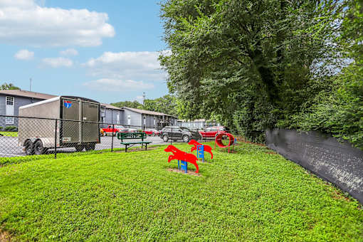 A playground with red and blue slides is in the foreground of a grassy area.