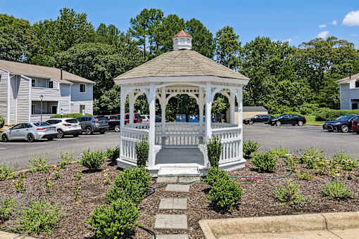 A gazebo is surrounded by a flowerbed and steps leading up to it.
