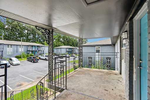 A view from a covered patio looking out to a parking lot and apartment buildings.