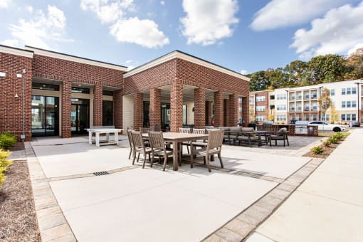 a patio with tables and chairs in front of a brick building