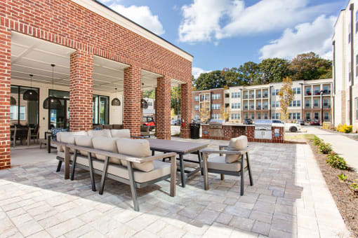 a patio with a table and chairs in front of a brick building