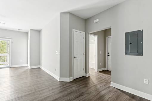 A room with a white door and a window with a view of a fence.