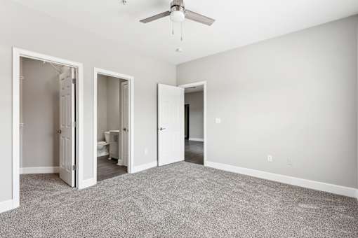 A room with a ceiling fan and carpeted floor.