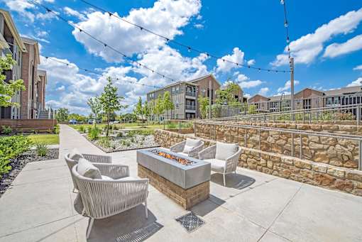 A patio with a fire pit and chairs.