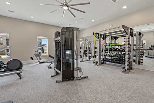 A gym with a variety of equipment including a treadmill, weights, and a bench.