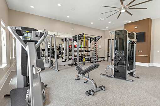 A spacious gym with a variety of equipment including treadmills, weights, and a television.