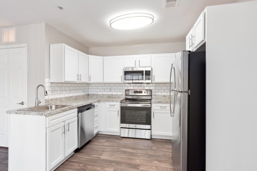 an empty kitchen with white cabinets and stainless steel appliances