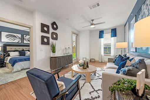 A well-lit, modern living room with a blue chair and a white couch.