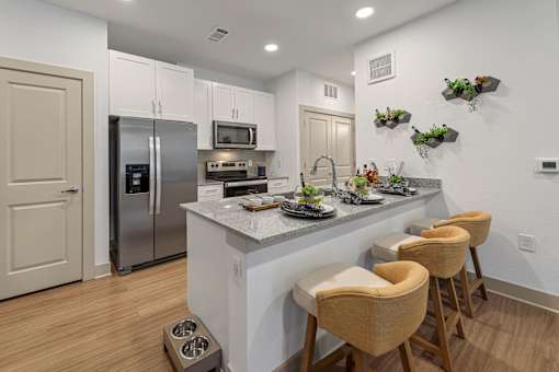 A kitchen with a refrigerator, microwave, oven, and sink.