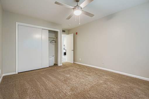 A room with a carpeted floor and a ceiling fan.