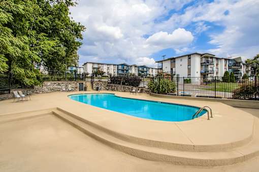 A swimming pool surrounded by a concrete deck and a fence.