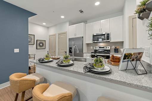 A kitchen with a countertop and two chairs.