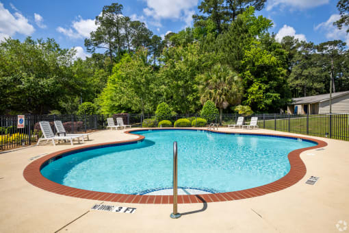 a resort style pool with chairs and a fence around it