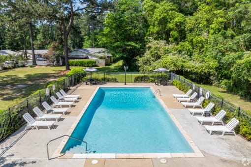 a swimming pool with white chairs and a fence around it