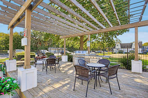 A wooden pergola with chairs and tables is set up for outdoor dining.