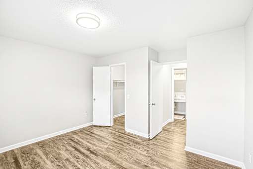 A white room with a light on the ceiling and a wooden floor.