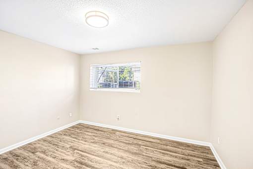 Empty room with a window and wooden flooring.