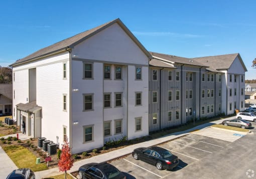 a large white apartment building with cars parked in front of it