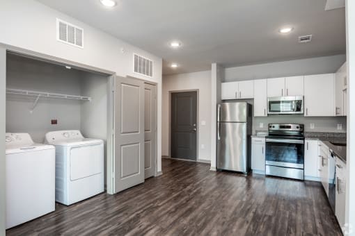 a laundry room with white cabinets and stainless steel appliances
