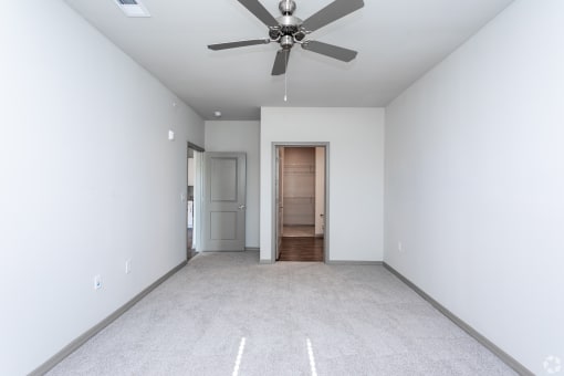 a bedroom with white walls and a ceiling fan