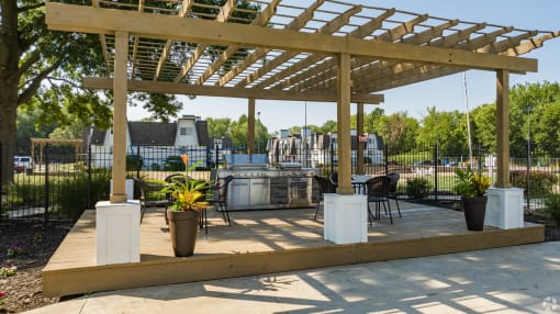 a patio with a pergola and a grill