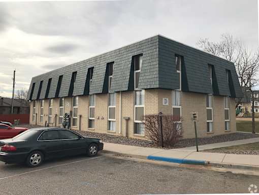 A black car is parked in front of a building with a grey roof.