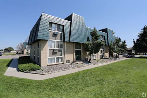 A modern house with a green roof and a well-maintained lawn in front.