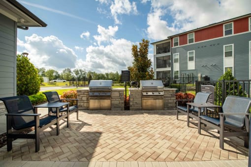 a patio with two barbecue grills and chairs on it