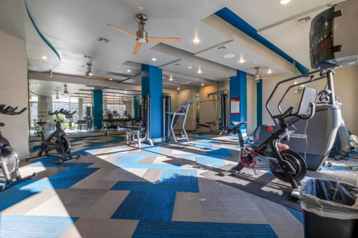 a gym with exercise machines and bikes in a clubhouse