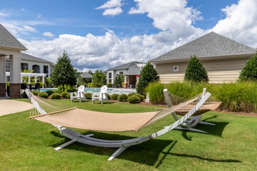 a pair of hammocks sit on the grass in front of a house