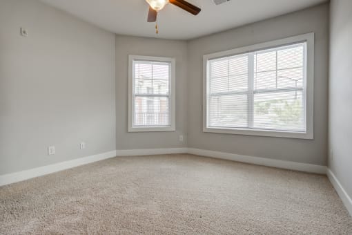 a bedroom with two windows and a ceiling fan