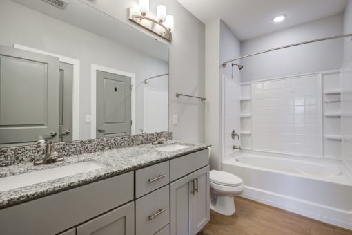 a bathroom with gray cabinets and a white bathtub