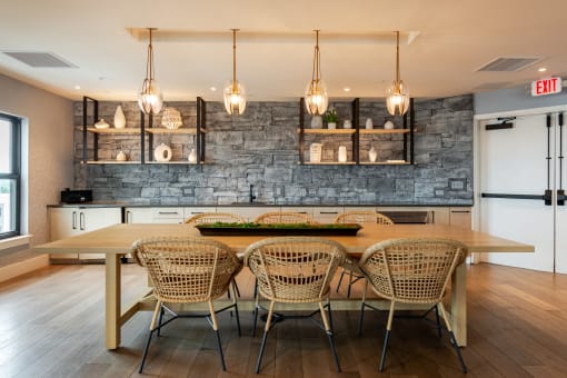 a dining area with a wooden table and chairs and a brick wall behind it