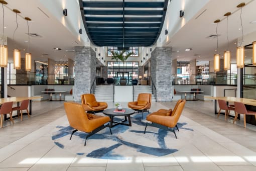 a large lobby with orange chairs and tables